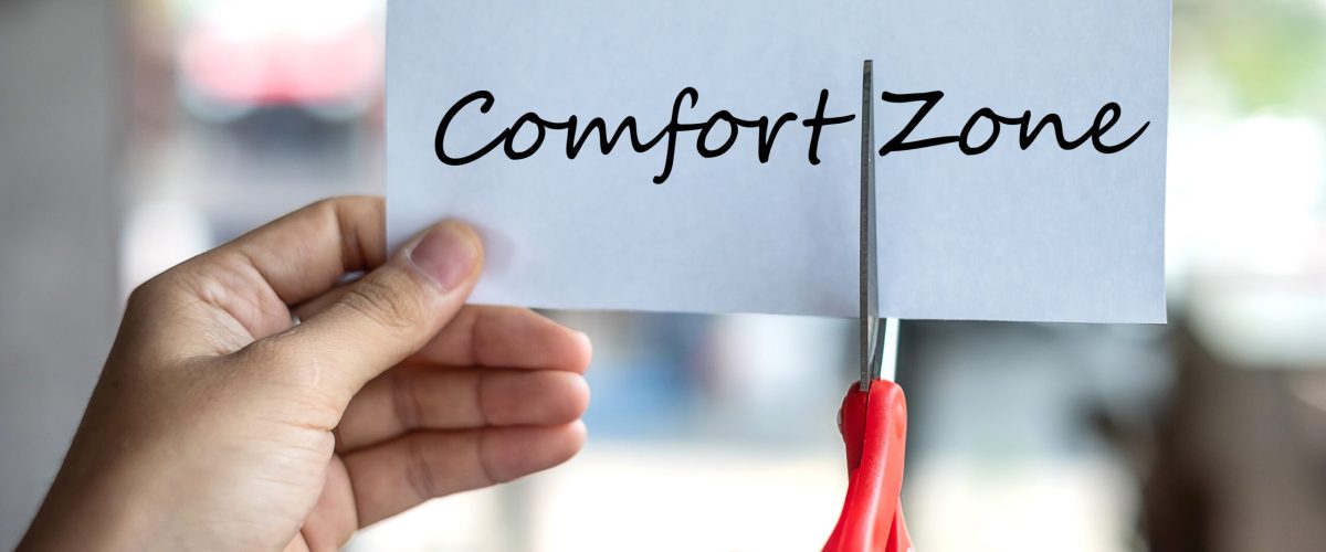 Business man hand holding red scissors and cutting white paper with the text Comfort Zone, change word to Zone. challenge, positive thinking and success concept