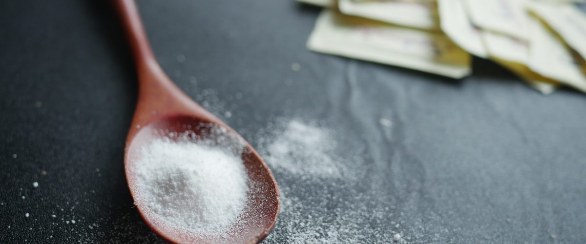 spoon of white sweetener on a black background