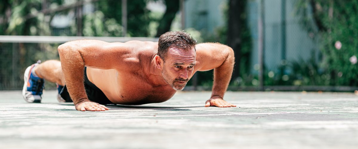 Fitness middle aged man doing push-ups. Male athlete exercising outdoors. Sports and active lifestyle. Body goals. Horizontal shot